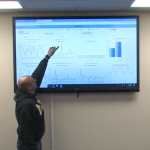 man in conference room reviewing dashboard analytics with employees